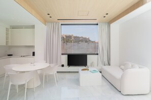 Una sala moderna con comedor, un sofá y un ventanal con vista a un edificio.
