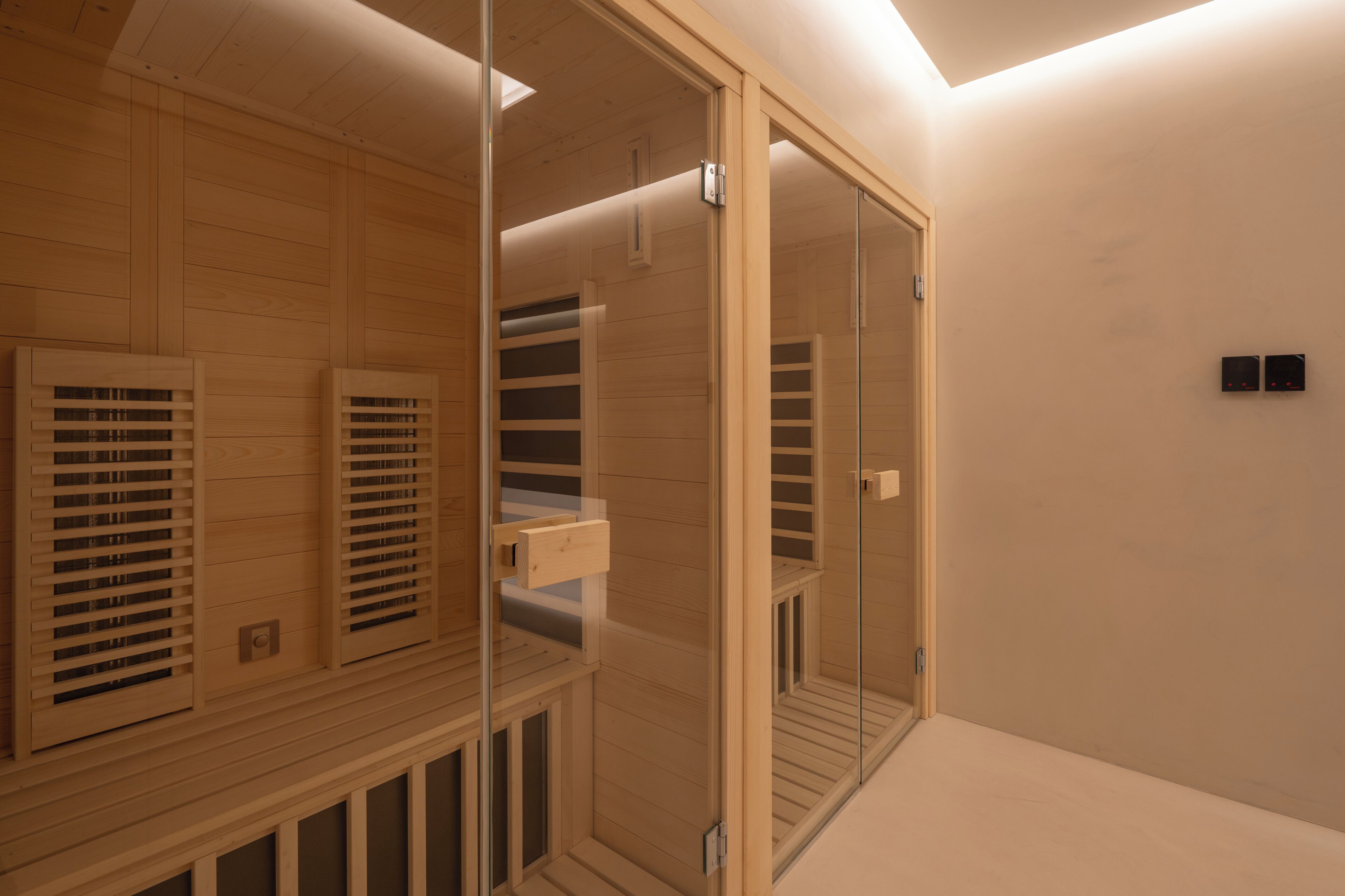 Una habitación moderna y luminosa con paneles de madera, una puerta de cristal y estanterías empotradas.