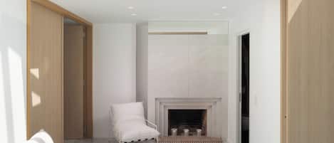 A modern interior with a fireplace, a white armchair, and a sofa.