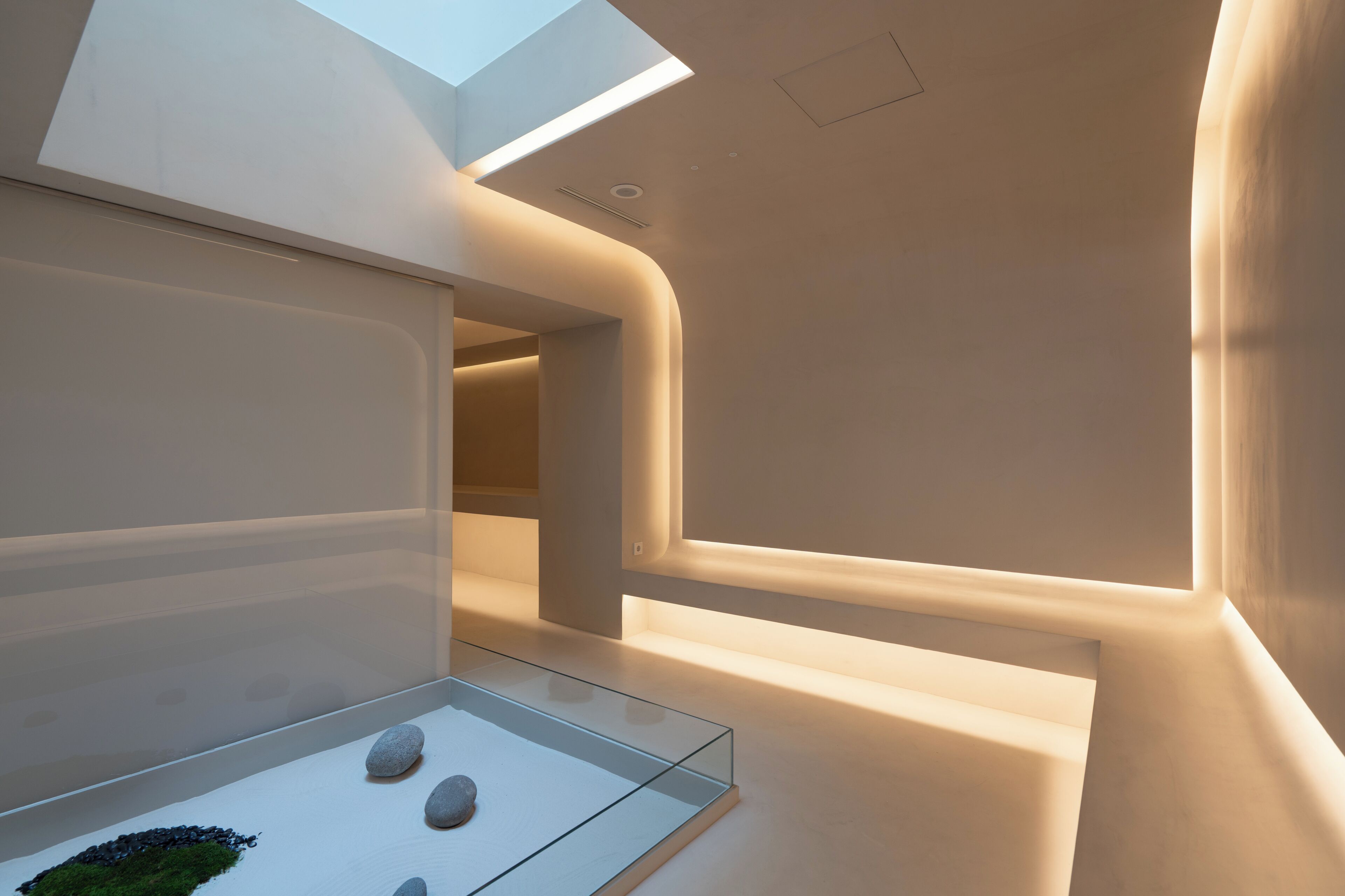 Um interior moderno com uma vitrine de vidro contendo pedras, iluminação embutida e um claraboia.