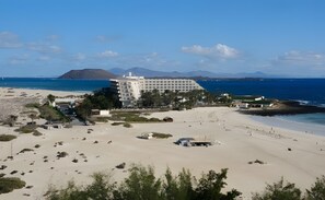 Ein Küstenhotel mit Strandblick, mehreren Gebäuden und einer Bergkulisse im Hintergrund.
