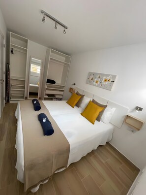 A hotel room with a bed, a wardrobe, a bedside table, and a wall-mounted artwork. - Vacation Apartment 'Digital  Zen Wifi Free' with Private Terrace, Wi-Fi and Air Conditioning (Corralejo)