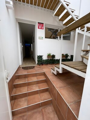 Un escalier menant à un palier où se trouvent un banc en bois et des plantes en pot.