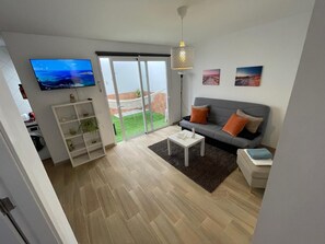 Ein modernes Wohnzimmer mit grauem Sofa, weißem Couchtisch und an der Wand montiertem Fernseher.