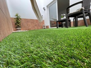 A well-maintained artificial lawn with a patio area featuring a chair and a small table. - Vacation Apartment 'Digital  Zen Wifi Free' with Private Terrace, Wi-Fi and Air Conditioning (Corralejo)
