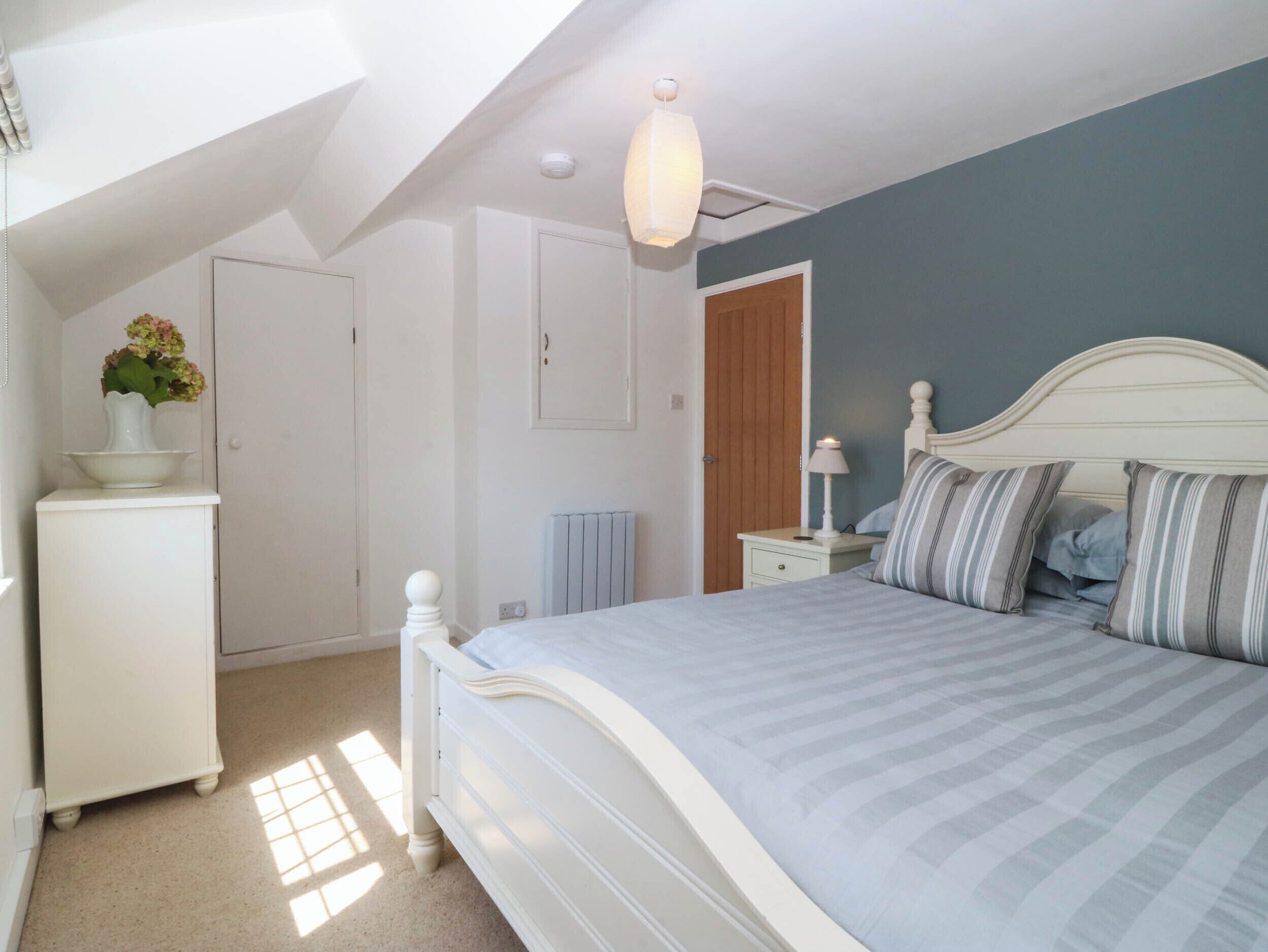 A bedroom with a bed, a dresser, a radiator, and a door.