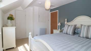 A bedroom with a bed, a dresser, a radiator, and a door.