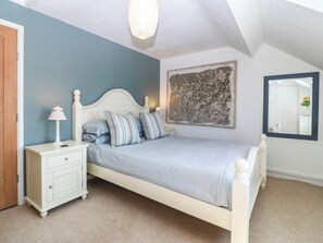 A bedroom with a bed, nightstand, and a wall-mounted mirror.