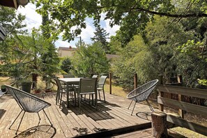 Une terrasse extérieure avec une plateforme en bois, une table et des chaises, et un hamac.