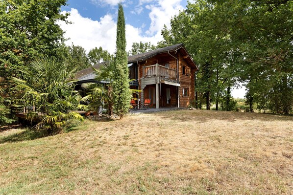 Une cabane en bois dotée d’un porche et d’un espace extérieur aménagé et abrité.