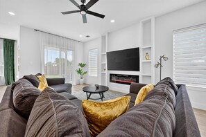 Ein modernes Wohnzimmer mit einer Couch, einem Couchtisch, einem Flachbildfernseher und einem Kamin.