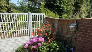 An outdoor patio with a round table, two chairs, a bottle of champagne, a glass, and a plate of olives. - Moss Retreat Sleeps 2, Balcony/garden/parking/pubs (Nantwich)