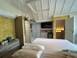 A bedroom with a bed, a dresser, a TV, and a wardrobe. - Beachfront Bungalow with Staff in Carneiros (Praia dos Carneiros)