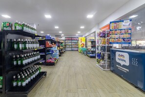 Un pasillo de supermercado con estantes llenos de diversos productos, entre ellos bebidas y artículos para el hogar.