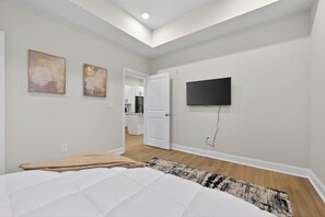 Quarto com uma cama, televisão fixada na parede e porta de acesso a um banheiro.