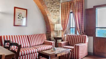 A room with a stone wall, a sofa, a chair, a table, and a window with curtains.