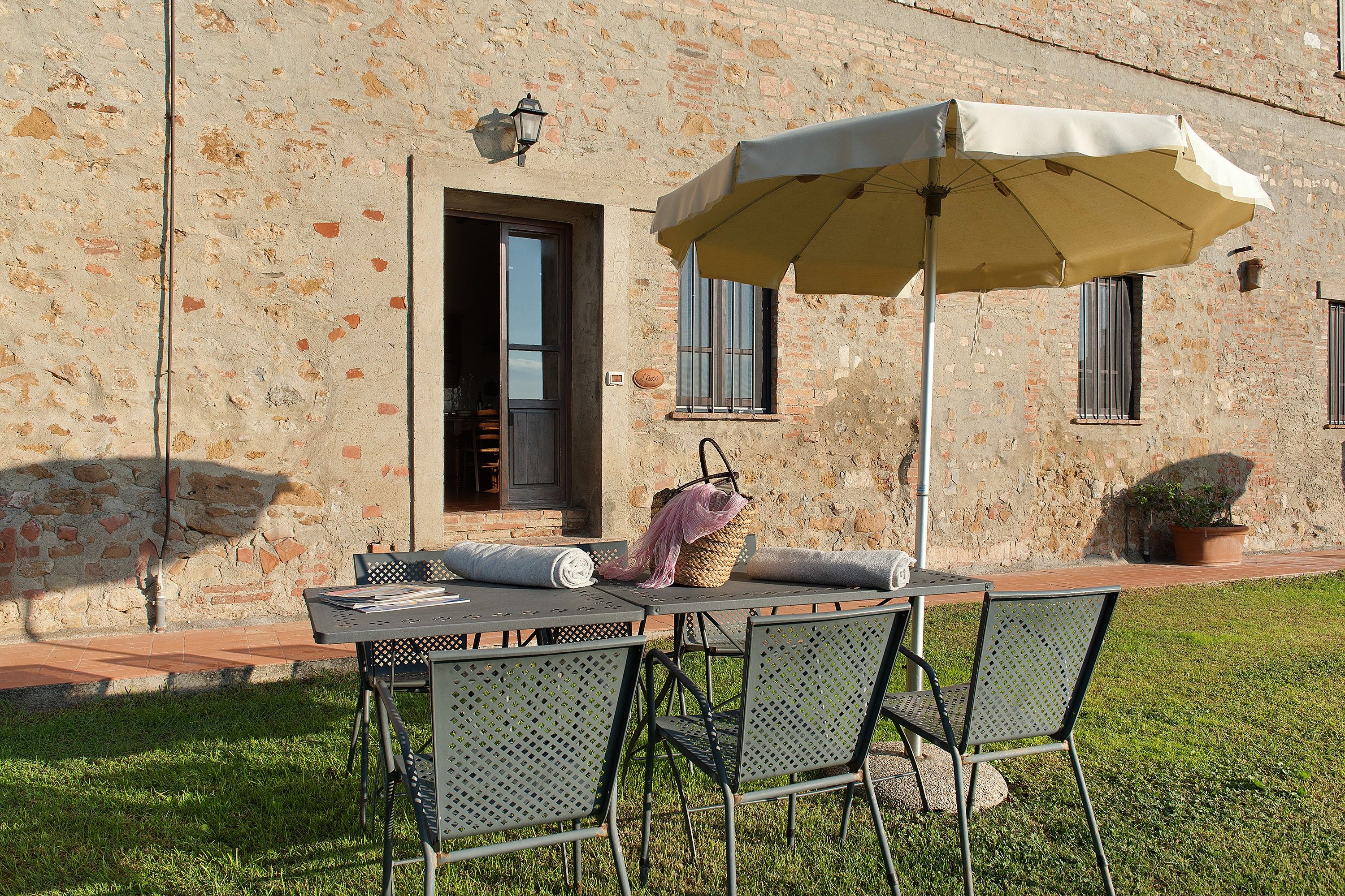 An outdoor seating area with a table and chairs, a hanging basket, and a potted plant.