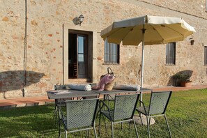 Un área de estar al aire libre con una mesa y sillas, una cesta colgante y una planta en maceta.