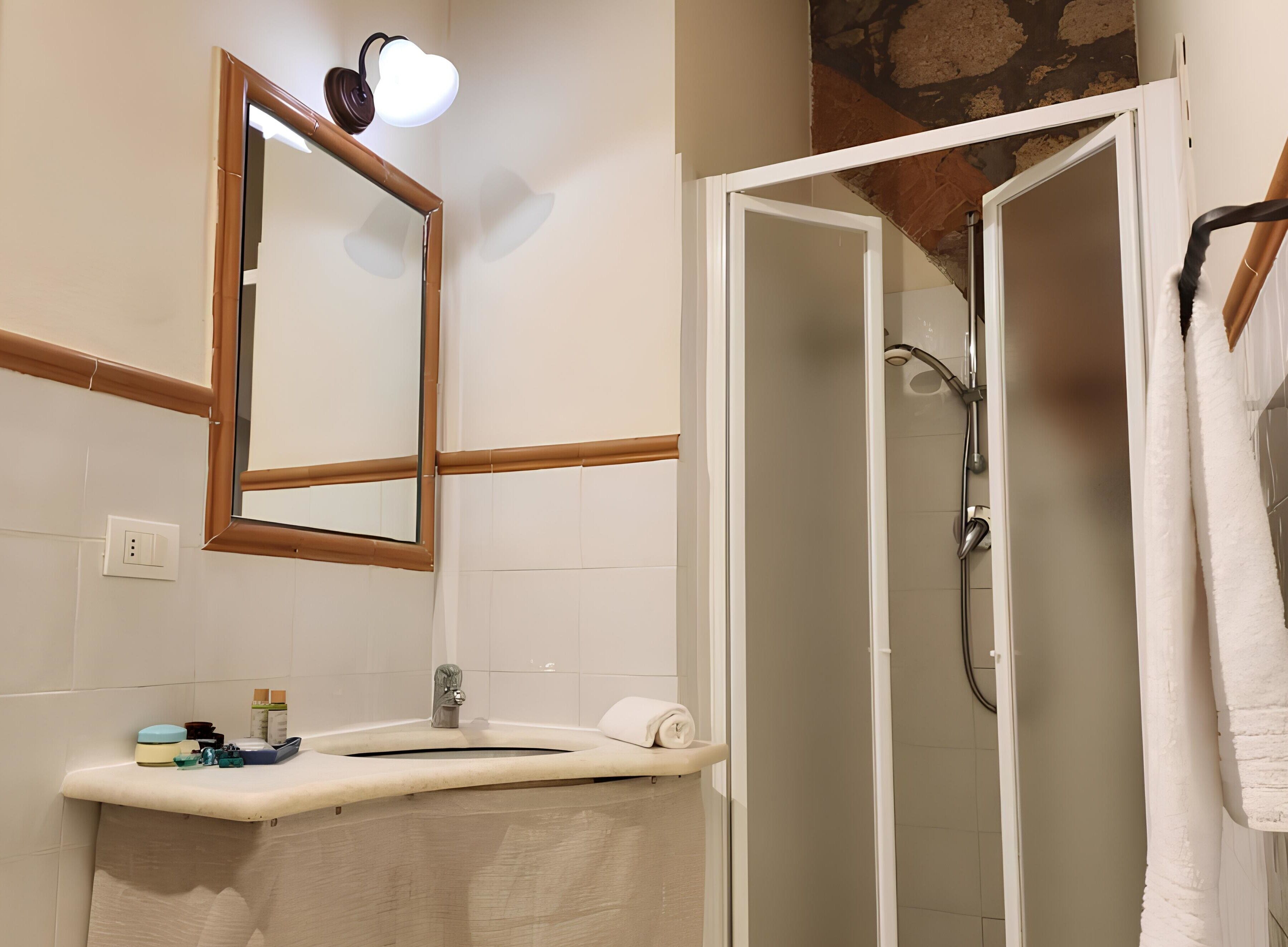 Une salle de bain équipée d’un miroir, d’un lavabo, d’une douche et d’un porte-serviettes.
