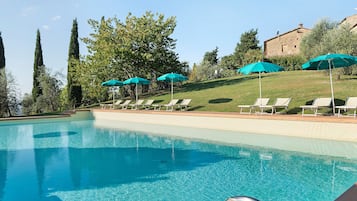 A swimming pool with clear blue water, surrounded by lounge chairs and umbrellas.