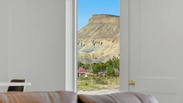 A bedroom with a bed and a door leading to a view of a mountainous landscape.