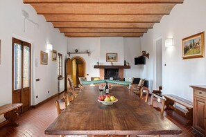 Un comedor con una larga mesa de madera, sillas, una chimenea y un televisor montado en la pared.