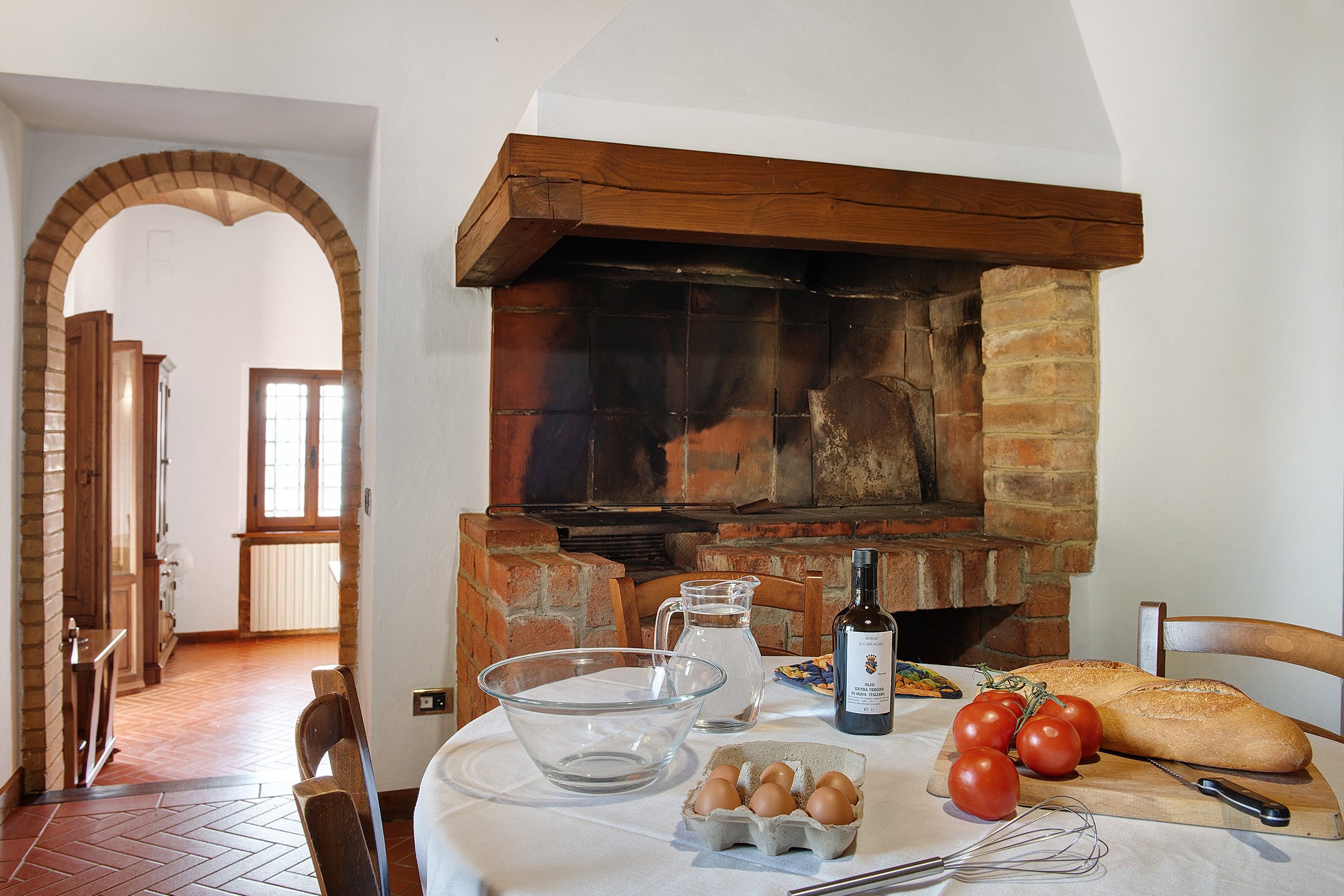 Eine Küche mit einem Backofen, einem Tisch mit Eiern, Tomaten, Brot und einer Flasche.