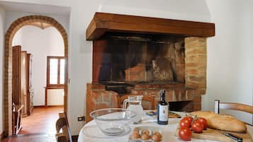 Eine Küche mit einem Backofen, einem Tisch mit Eiern, Tomaten, Brot und einer Flasche.