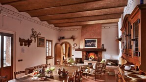 A traditional interior with a fireplace, wooden furniture, and a dining area. - Caccia - Spacious Apartment with Views of the Tuscan Hills (Gambassi Terme)