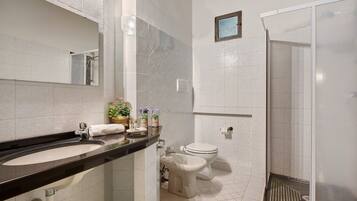 A bathroom with a black countertop sink, a white toilet, and a glass shower enclosure.