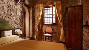 A room with a bed, a chair, a window with curtains, and a wooden door. - Caccia - Spacious Apartment with Views of the Tuscan Hills (Gambassi Terme)