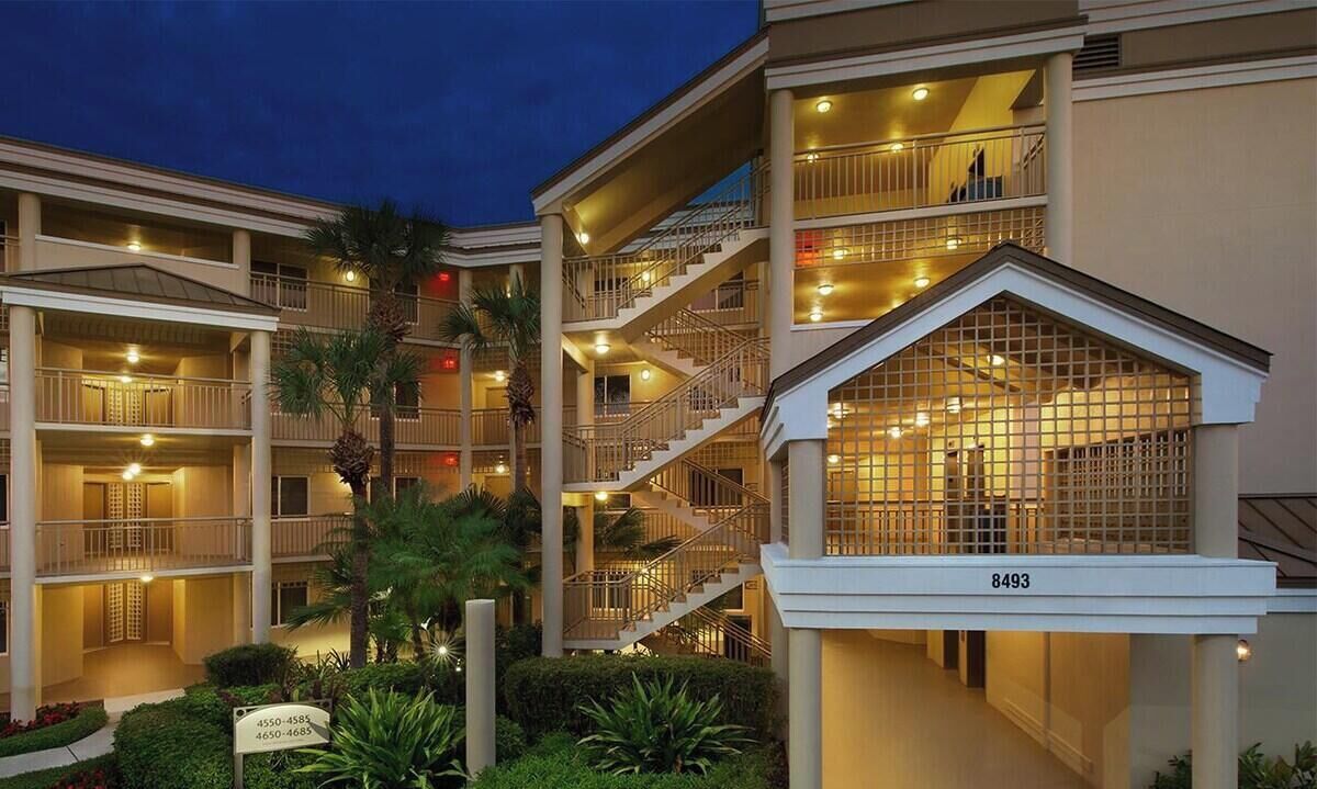 Un hotel de varios pisos con balcones, una escalera central y una fachada bien iluminada.