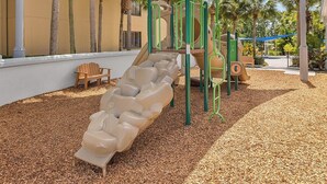 Un parque infantil con un tobogán, estructuras para escalar y un banco.