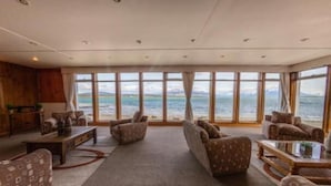 Un salón espacioso con ventanas amplias, chimenea y vistas al mar.