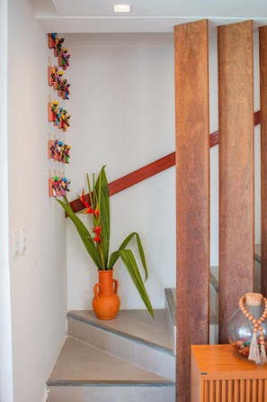 Eine Treppe mit einem Blumentopf, eine Holzkommode und eine Wand mit Wanddekorationen.