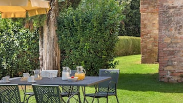 An outdoor dining area with a table set for two, a pitcher of water, a glass of milk, and a bowl of cereal with a strawberry.