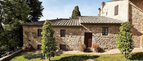 A stone building with a tiled roof, a central door, and small windows.