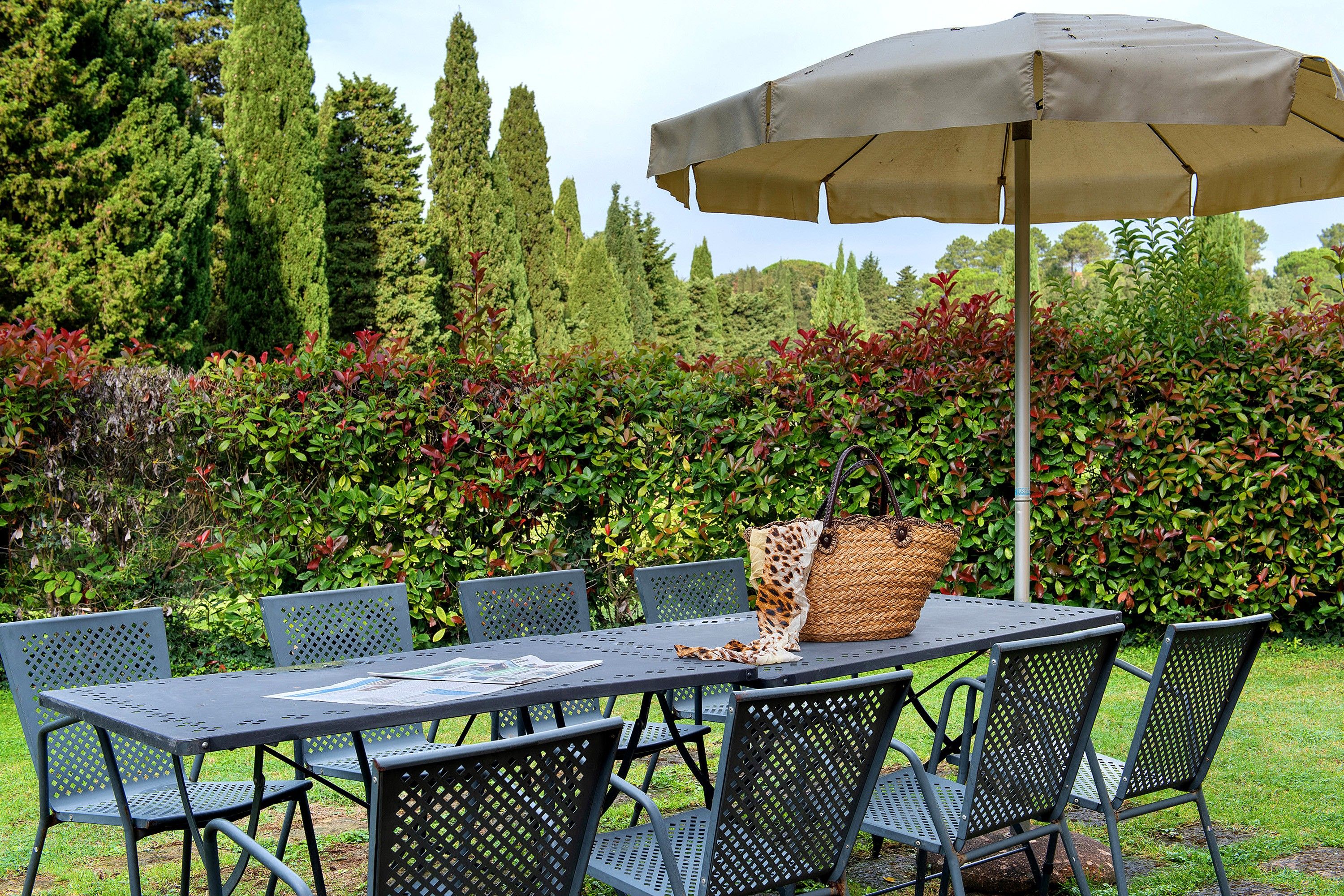 An outdoor dining area with a table and chairs, a woven basket, and a large umbrella.