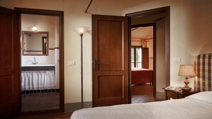Ein Hotelzimmer mit einem Bett, einem Nachttisch mit Lampe, einem Spiegel und einer offenen Tür zu einem Badezimmer.