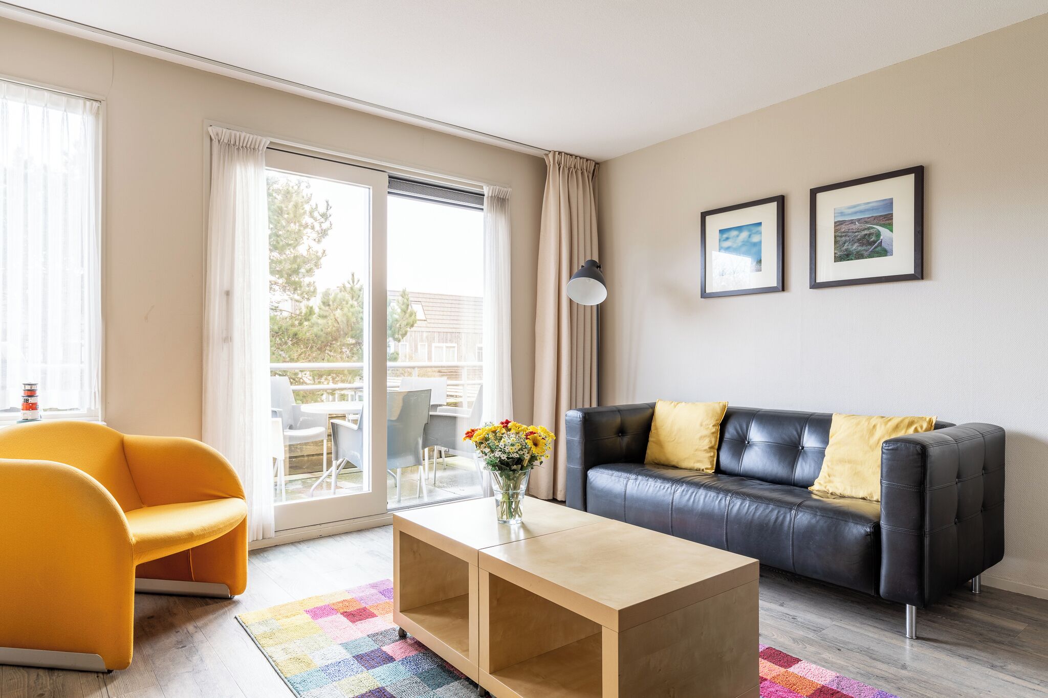 Een moderne woonkamer met een bank, een salontafel en een kleurrijk vloerkleed.