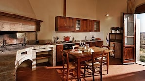 Eine Küche mit Backofen, Holzschränken und einem Essbereich mit Tisch und Stühlen.