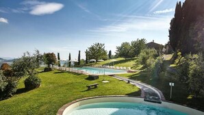 Ein Schwimmbecken mit einer umlaufenden Terrasse, einer Brücke und Blick auf die Landschaft.