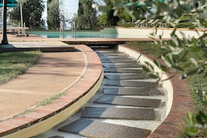 A curved stone pathway leading to a pool area with a view of the surrounding landscape.