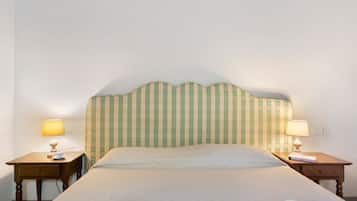 Habitación de hotel con una cama individual, dos mesitas de noche y un cabecero con estampado de cuadros.