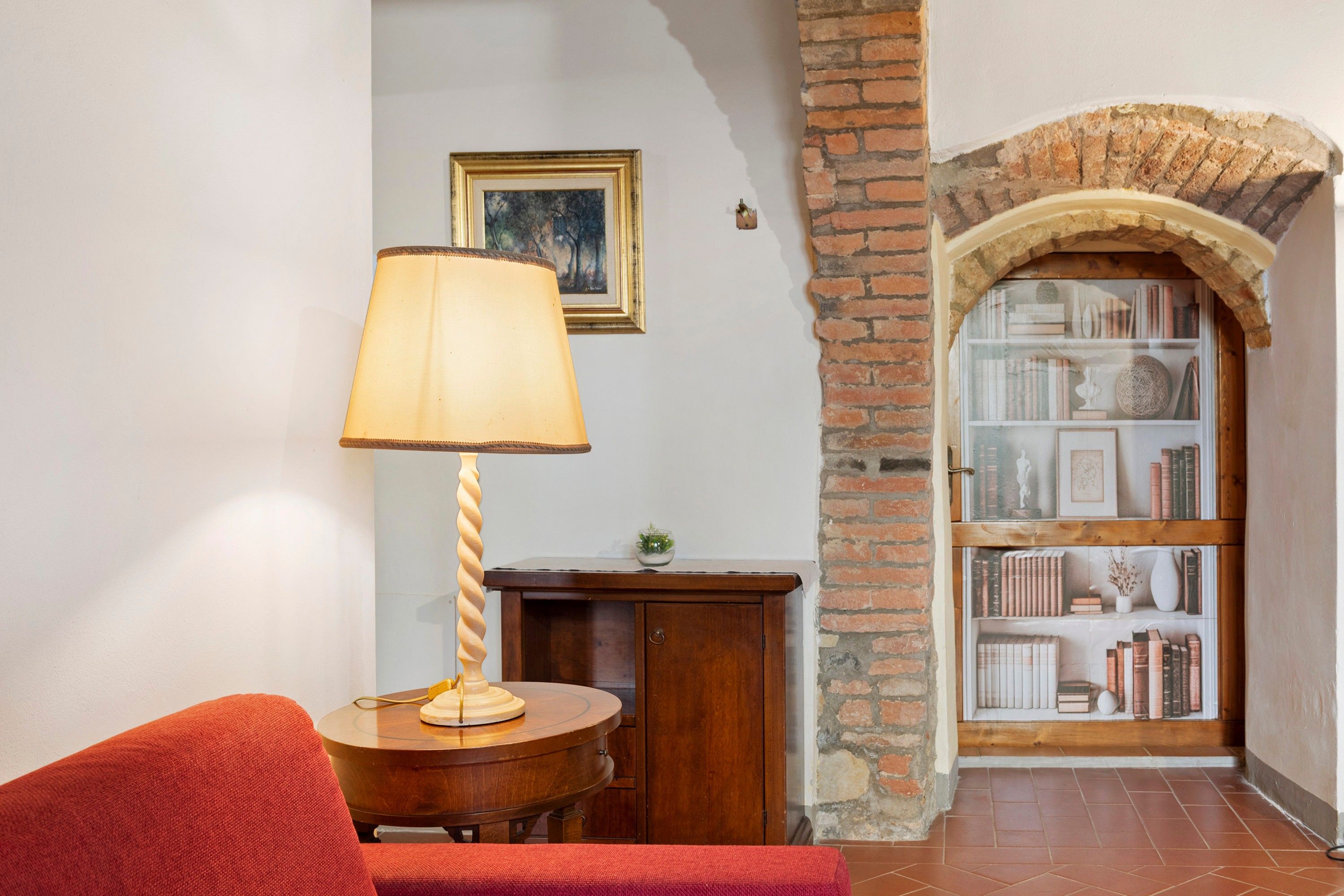 A cozy reading nook with a lamp, a small table, and a bookshelf.