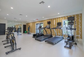 Une salle de sport équipée de tapis de course, de vélos d’appartement et de ballons d’exercice.