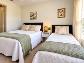 Une chambre d’hôtel avec deux lits, une table de chevet avec une lampe et deux tableaux accrochés au mur.