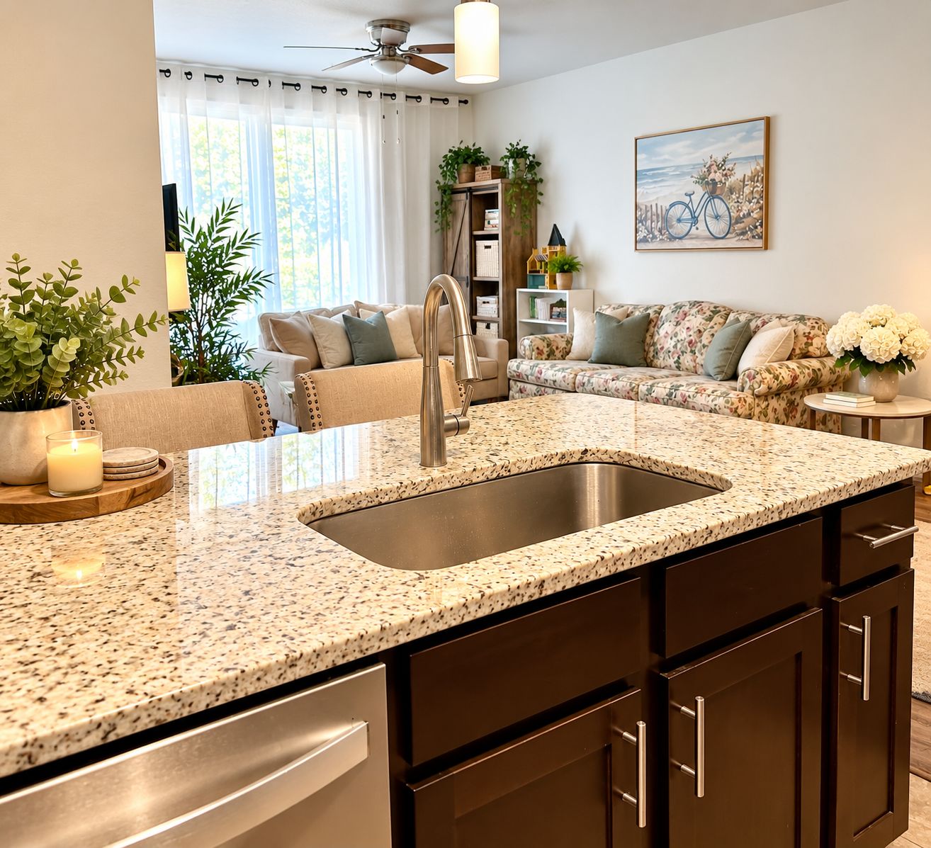 A modern kitchen with a granite countertop, stainless steel sink, and dark cabinetry.