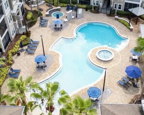 A swimming pool with lounge chairs and umbrellas, surrounded by a landscaped area with palm trees. - Summer Heaven Retreat near Universal Studious, Disney (Lake Buena Vista)
