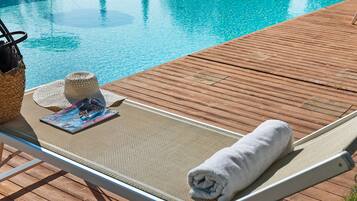 A poolside lounge chair with a towel, a magazine, and a hat.